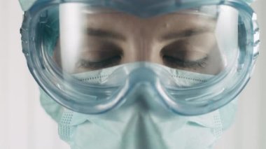 Koruyucu maskeli ve gözlüklü laboratuvar çalışanı araştırma ve operasyon yapıyor.