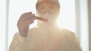 Bilim adamı kan örneğini biyolojik tehlike sembollü plastik torbaya koyuyor.