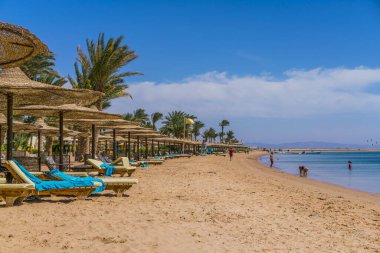 Şemsiyeli ve arka planda insanlar olan kumlu sahil.