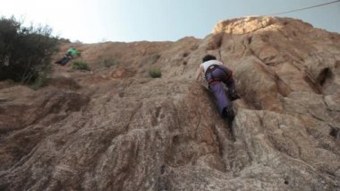Genç kadın kayaya tırmanıyor. 
