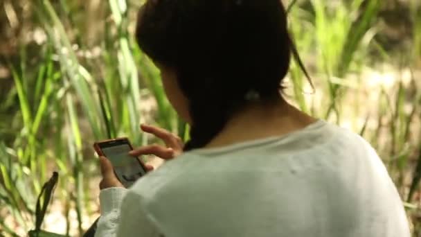 Дівчина використовує смартфон у лісі — стокове відео