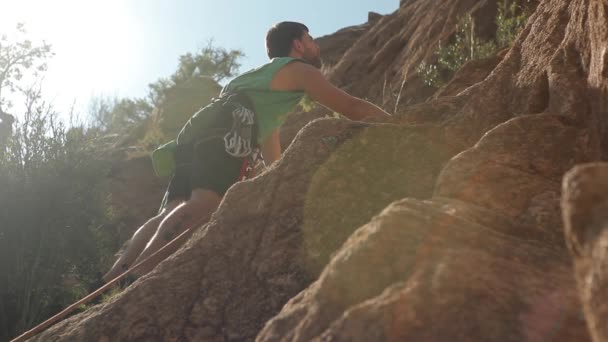 若い男が岩の上に登る — ストック動画