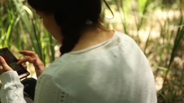 Chica usando smartphone en el bosque — Vídeos de Stock