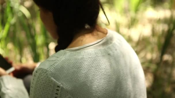 Девушка, использующая смартфон в лесу — стоковое видео