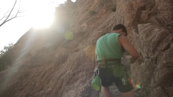 若い男が岩の上に登る — ストック動画