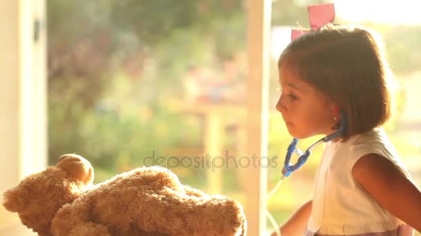 Дівчина грає лікаря з плюшевим ведмедем — стокове відео