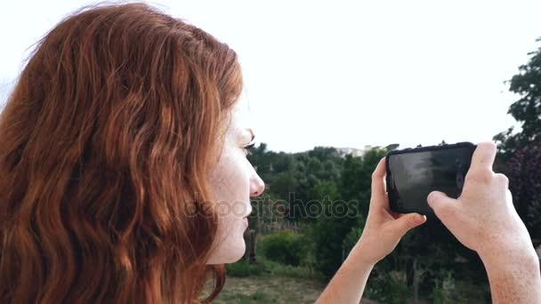 Молода руда дівчина фотографує — стокове відео