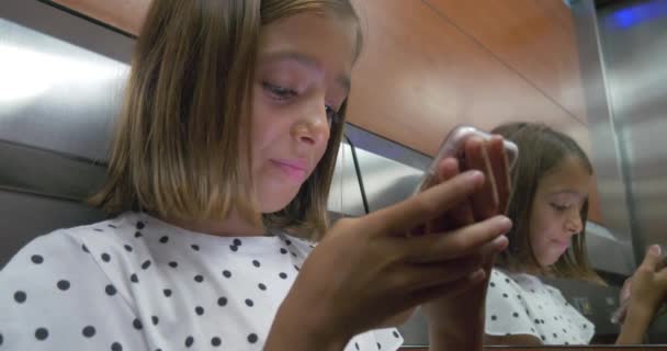 小可爱的漂亮女孩使用手机智能手机新技术在电梯 — 图库视频影像