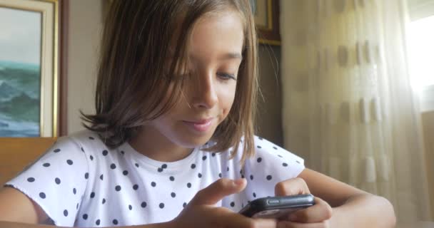 小可爱的漂亮女孩使用手机智能手机新技术坐在桌上 — 图库视频影像