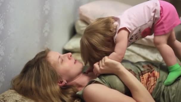 Η μητέρα παίζει με το μωρό στο κρεβάτι. — Αρχείο Βίντεο