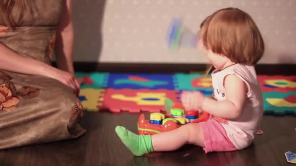 Ein Kind spielt mit einem Spielzeug auf dem Boden — Stockvideo