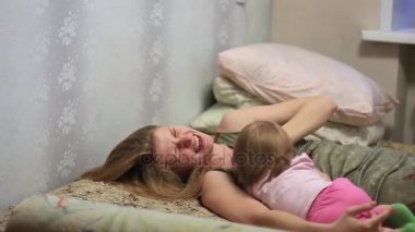 Anne yatakta bebekle oynuyor.