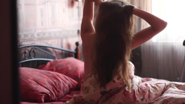 Een meisje wordt wakker in bed — Stockvideo