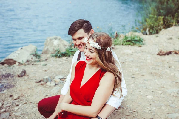 Casal sentado junto ao lago abraçando — Fotografia de Stock