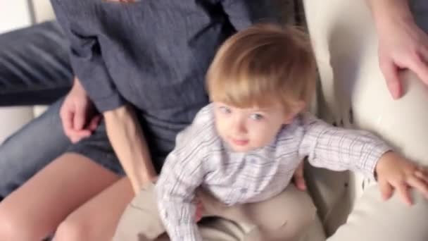 Una familia con un niño sentado en el sofá — Vídeos de Stock