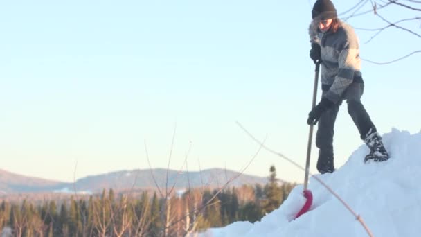 Hombre quitando nieve del techo con una pala — Vídeo de stock