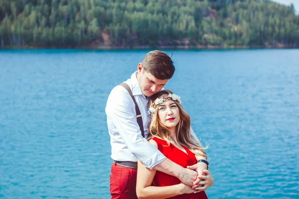 Casal em pé junto a um lago em um abraço — Fotografia de Stock