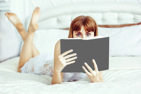 A girl with a book on the bed — Stock Photo, Image