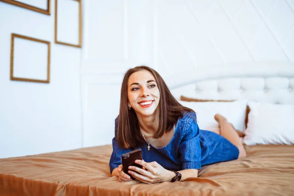 Dívka na posteli s telefonem — Stock fotografie