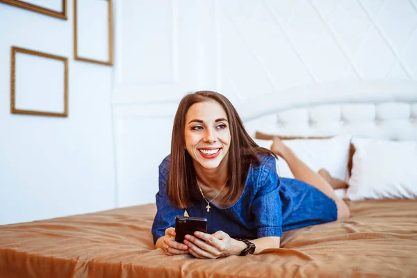 Flicka på säng med telefon — Stockfoto