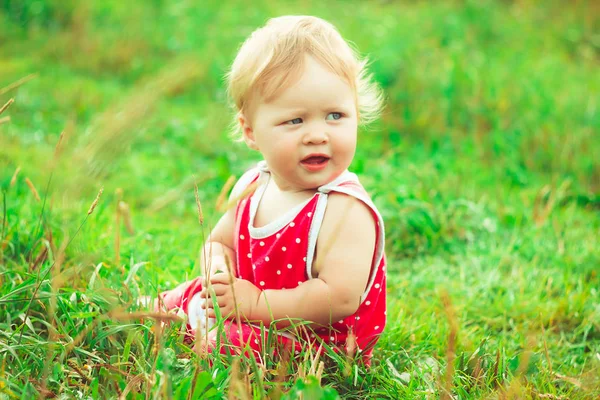 L'enfant est assis sur l'herbe — Photo