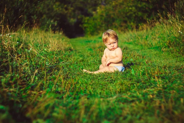 L'enfant est assis sur l'herbe — Photo