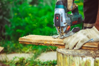 Elektrikli testere kullanarak koruma eldivenli adam