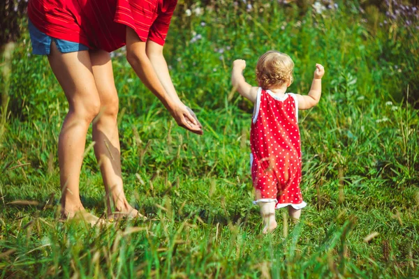 A criança aprende a andar na grama — Fotografia de Stock
