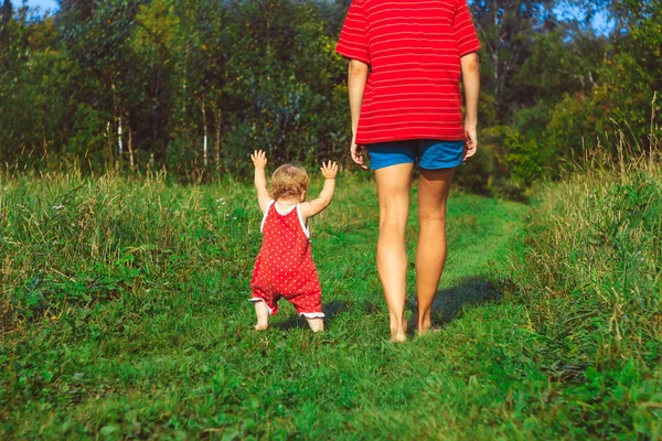 Het kind leert om op het gras te lopen — Stockfoto