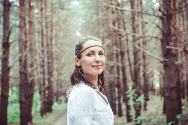 Bir kadın ağaçlar arasında duruyor