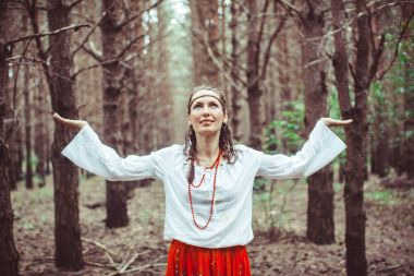 Bir kadın ağaçlar arasında duruyor