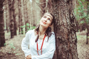 Bir kadın ağaçlar arasında duruyor