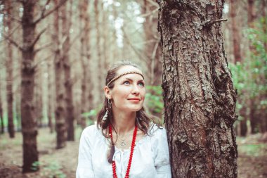 Bir kadın ağaçlar arasında duruyor