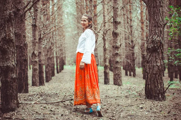 Bir kadın ağaçlar arasında duruyor