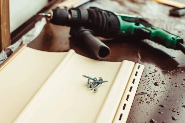 Screws lie next to the electric screwdriver — Stock Photo, Image