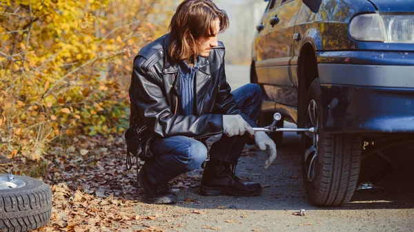 男は車の上でホイールを変更します。 — ストック写真