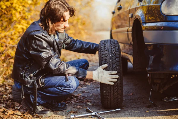 男は車の上でホイールを変更します。 — ストック写真