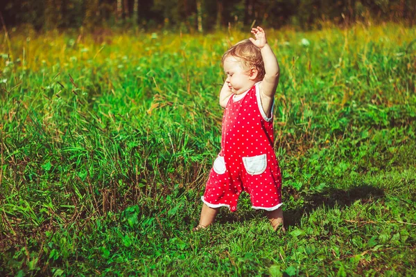 A criança aprende a andar na grama — Fotografia de Stock