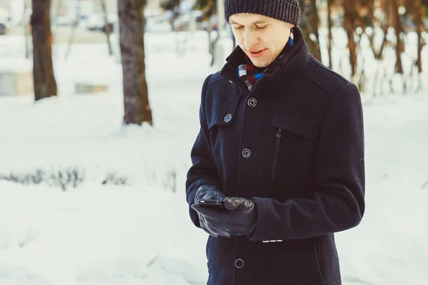 Facet patrzy na telefon w zimie — Zdjęcie stockowe
