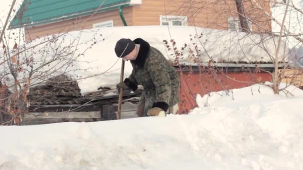 Мужчина стоит в снегу в деревне — стоковое видео