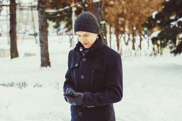 El tipo mira el teléfono en invierno — Foto de Stock