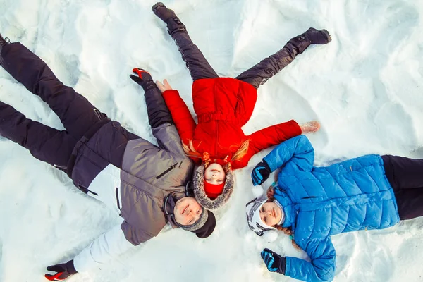 Rodzina z dzieckiem leżącego w śniegu — Zdjęcie stockowe