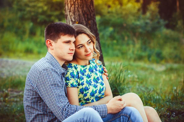 Pareja cariñosa abrazándose sentada en el bosque . — Foto de Stock