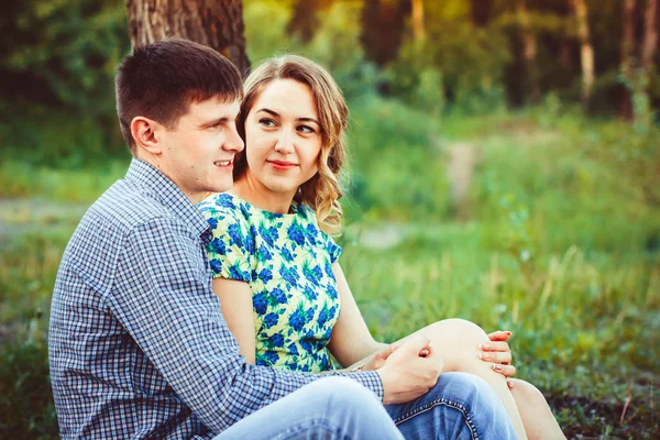 Pareja cariñosa abrazándose sentada en el bosque . — Foto de Stock