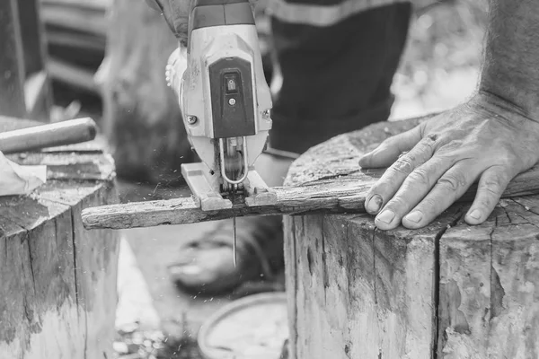 Homme avec gants de protection utilisant une scie électrique — Photo