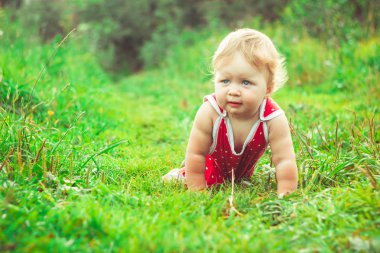 Çocuk çimlerin üzerinde oturuyor.