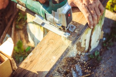 Elektrikli testere kullanarak koruma eldivenli adam