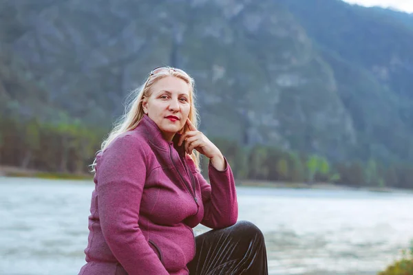 Una donna anziana seduta vicino al fiume — Foto Stock