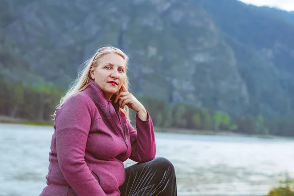 Starší žena sedící u řeky — Stock fotografie