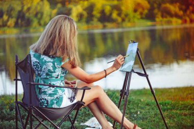 kız doğada bir resim çizer